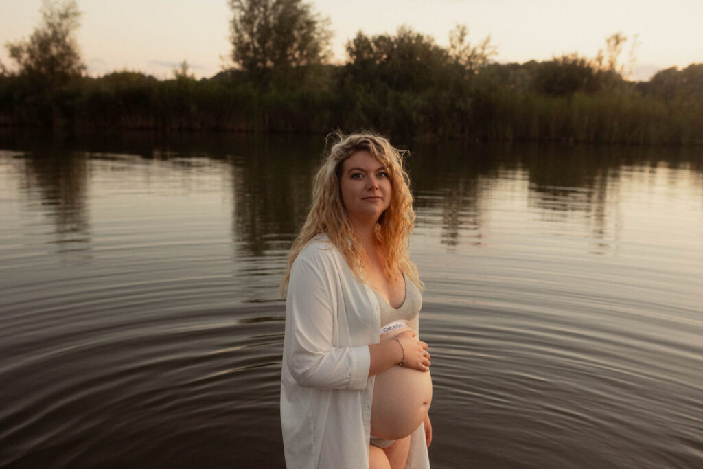 Vrouw kijkt recht in de camera met haar zwangere buik vastgehouden